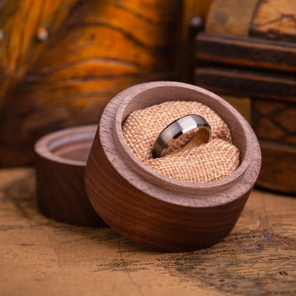 4mm silver brushed tungsten ring with whiskey barrel oak wood inlay. The ring is placed inside a round wooden box.