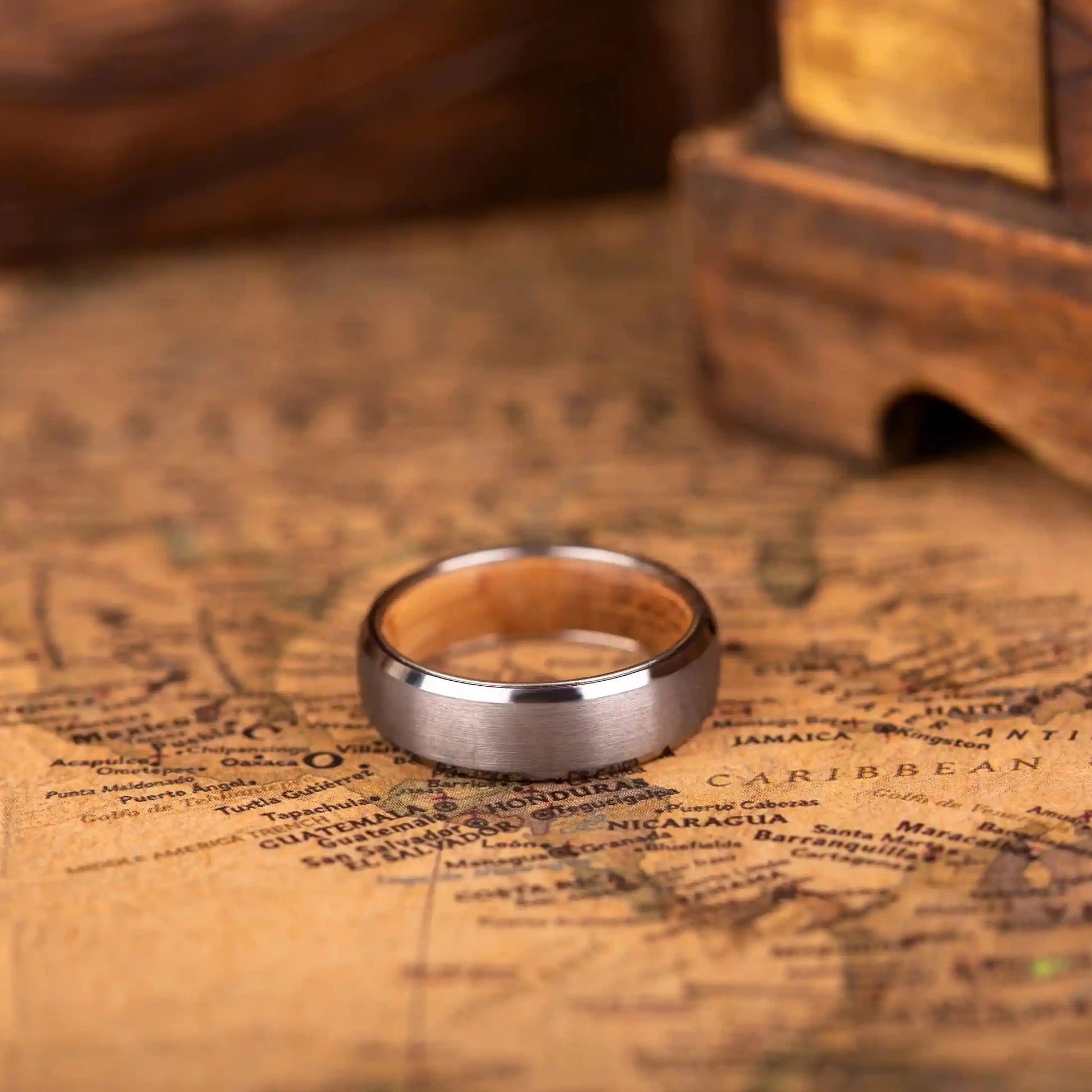 4mm silver brushed tungsten ring with whiskey barrel oak wood inlay. The ring is laying on a map