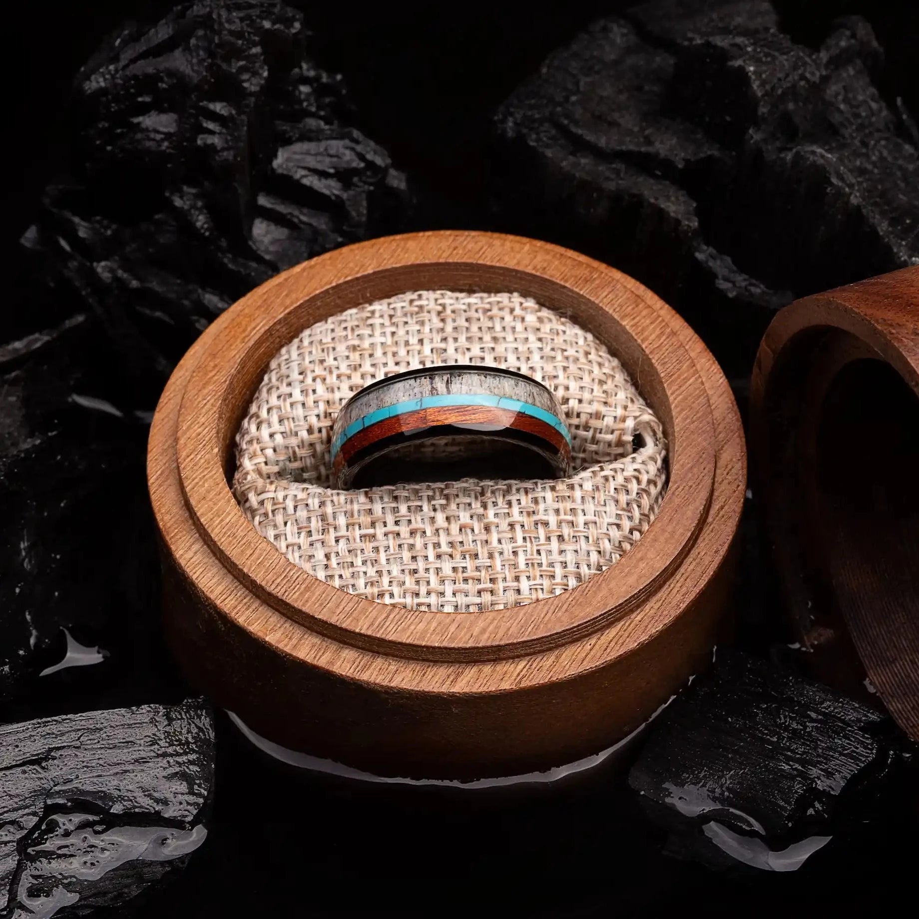 Brushed black tungsten ring with turquoise, koa wood and deer antler. The ring is placed inside a round wooden box.