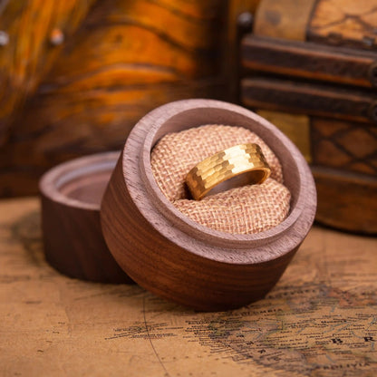 Faceted gold tungsten ring with walnut inlay. The ring is placed inside a round wooden box