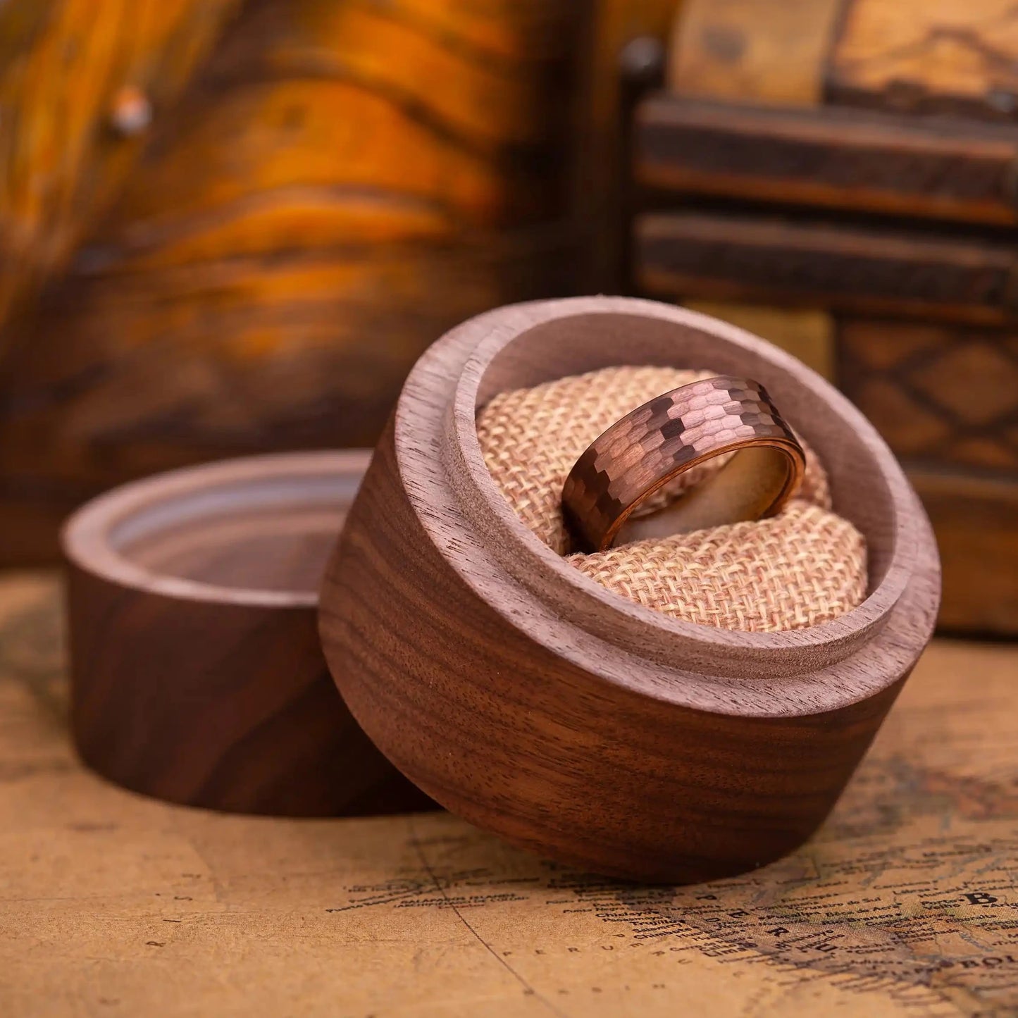 Red hammered tungsten ring with wenge wood inlay. The ring is placed inside a round wooden box.