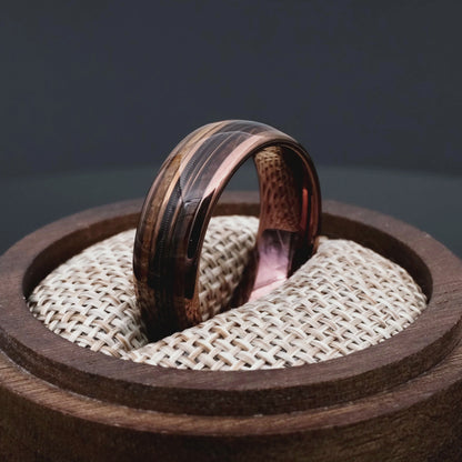 Brown Tungsten Ring with Guitar String in a central inlay. Ring in a round walnut woden box.