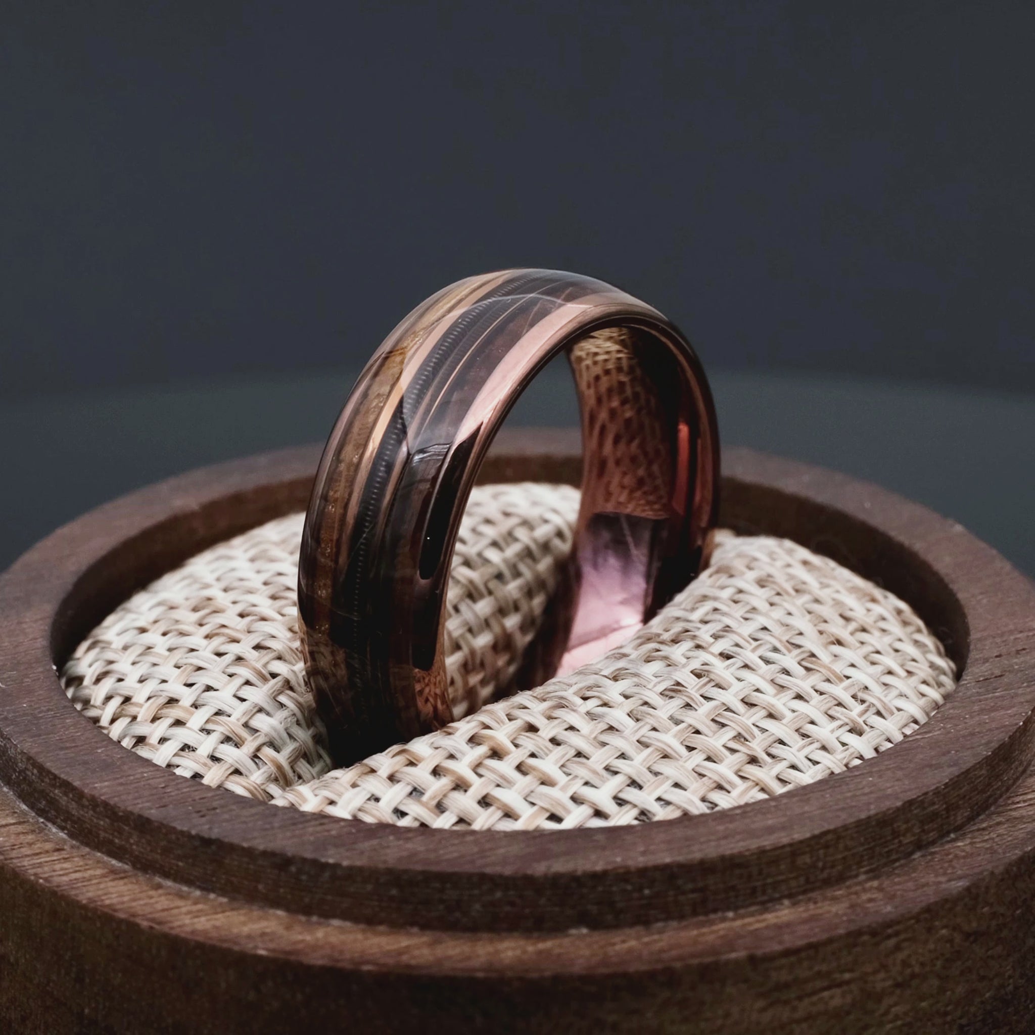 Brown Tungsten Ring with Guitar String in a central inlay. Ring in a round walnut woden box.